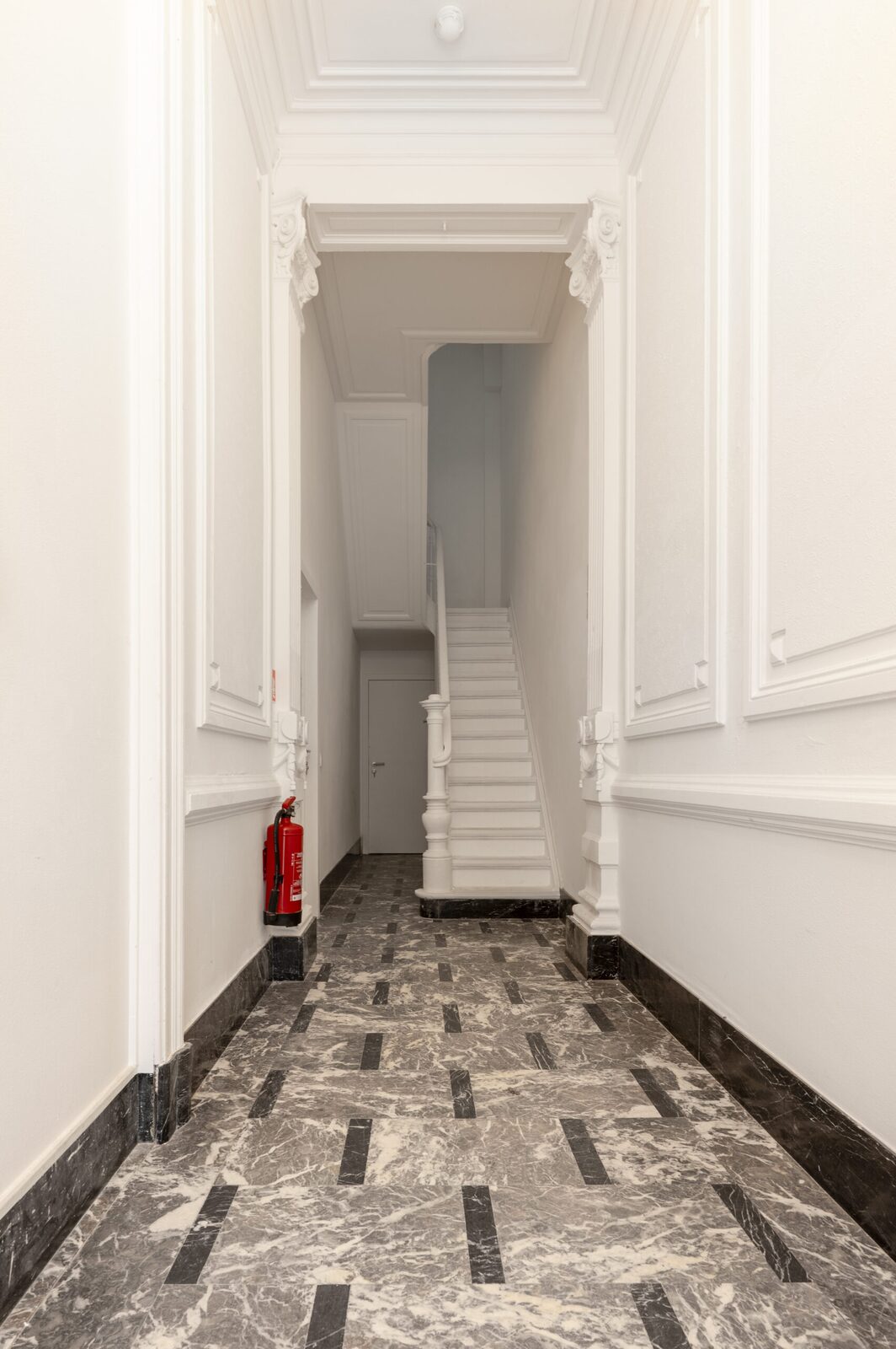 Gerestaureerde inkomhal met marmeren vloer en originele trap in Moonsstraat 26, Antwerpen